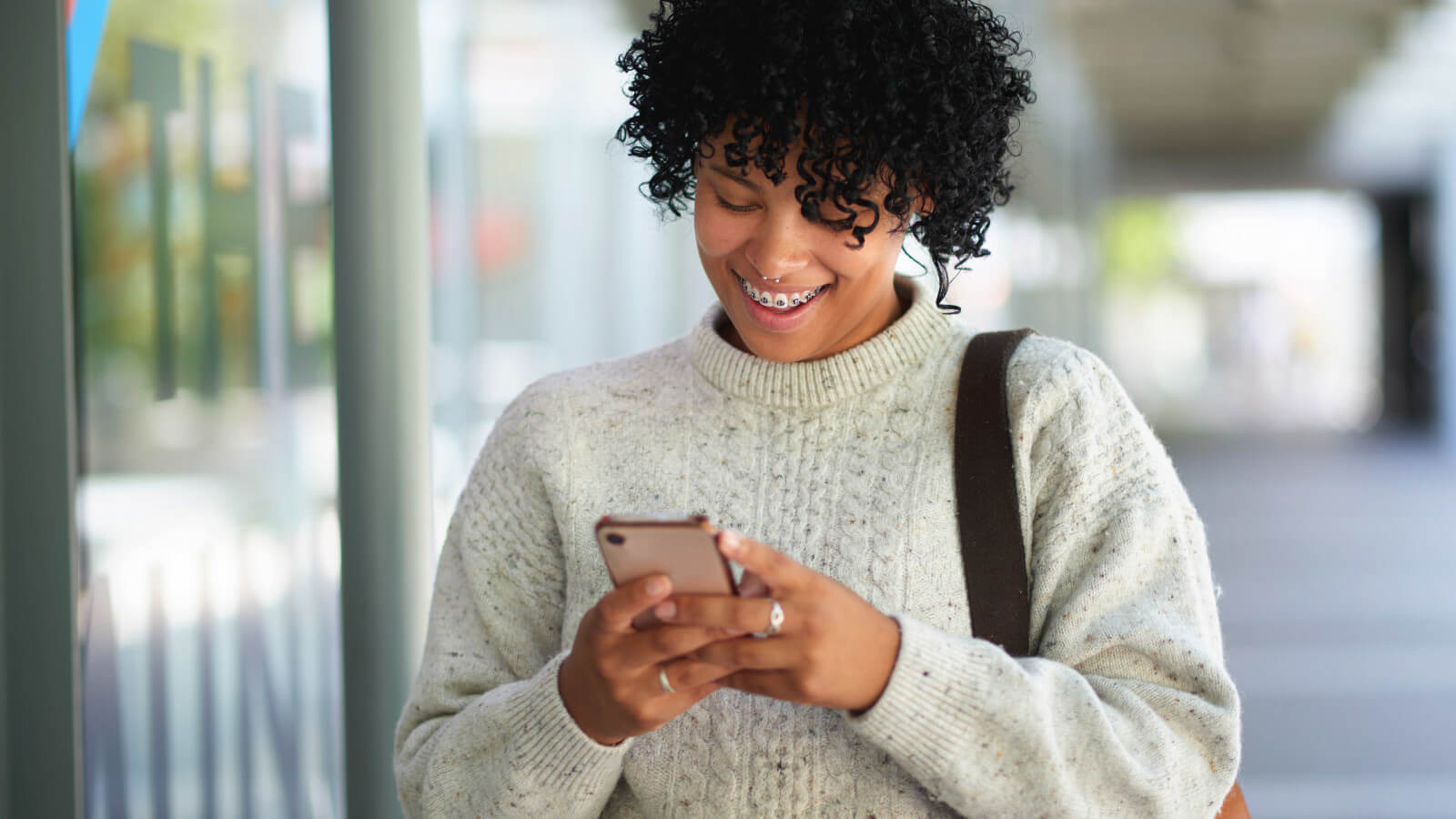 a young lady looks at her phone with a big smile